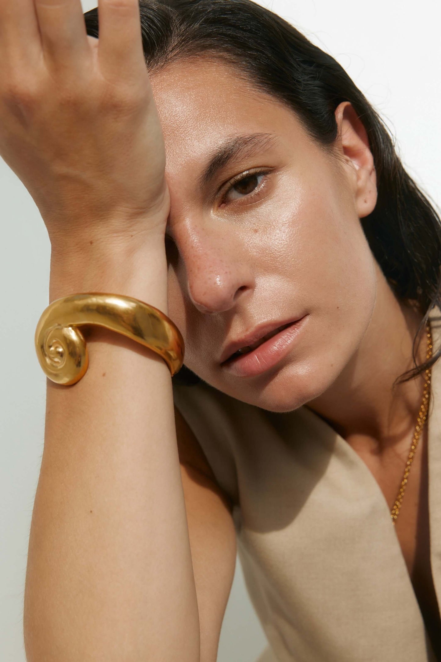 Model wearing a large, sculptural gold bracelet