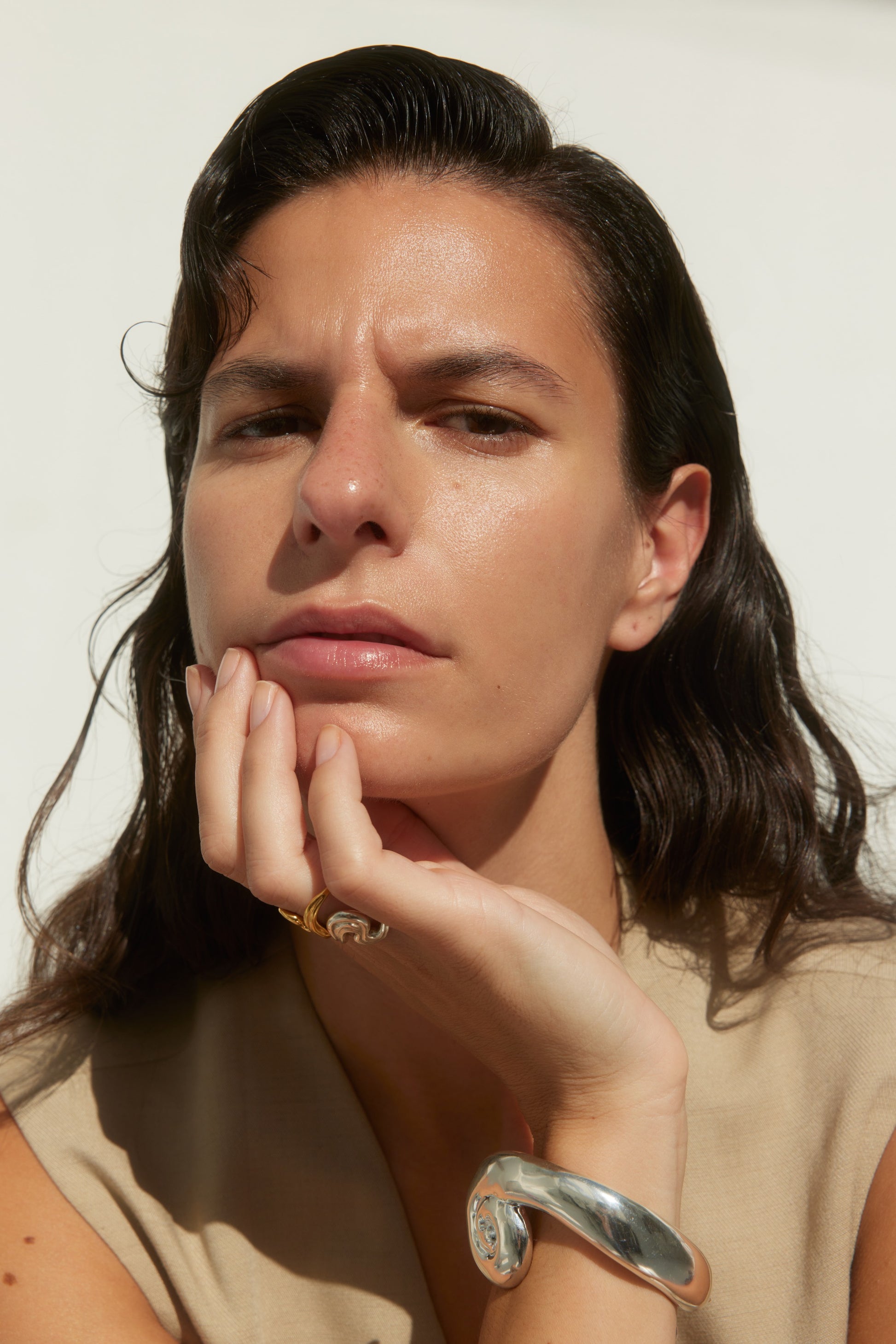 Model wearing rings and a large, sculptural silver bracelet