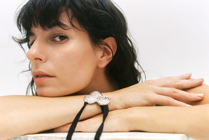 Model wearing silver bracelet with black silk ribbon