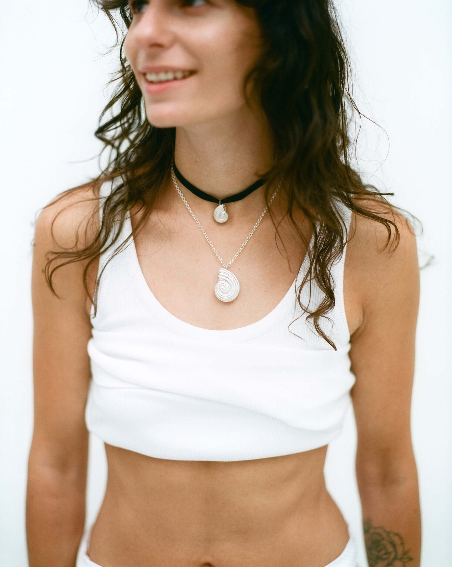 Female model smiling, wearing silver necklaces