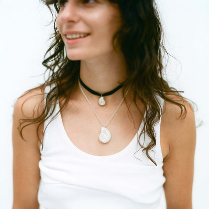 Female model smiling, wearing silver necklaces