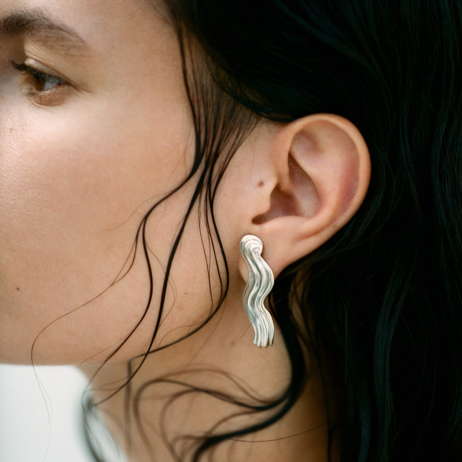 Model wearing wavy silver earrings