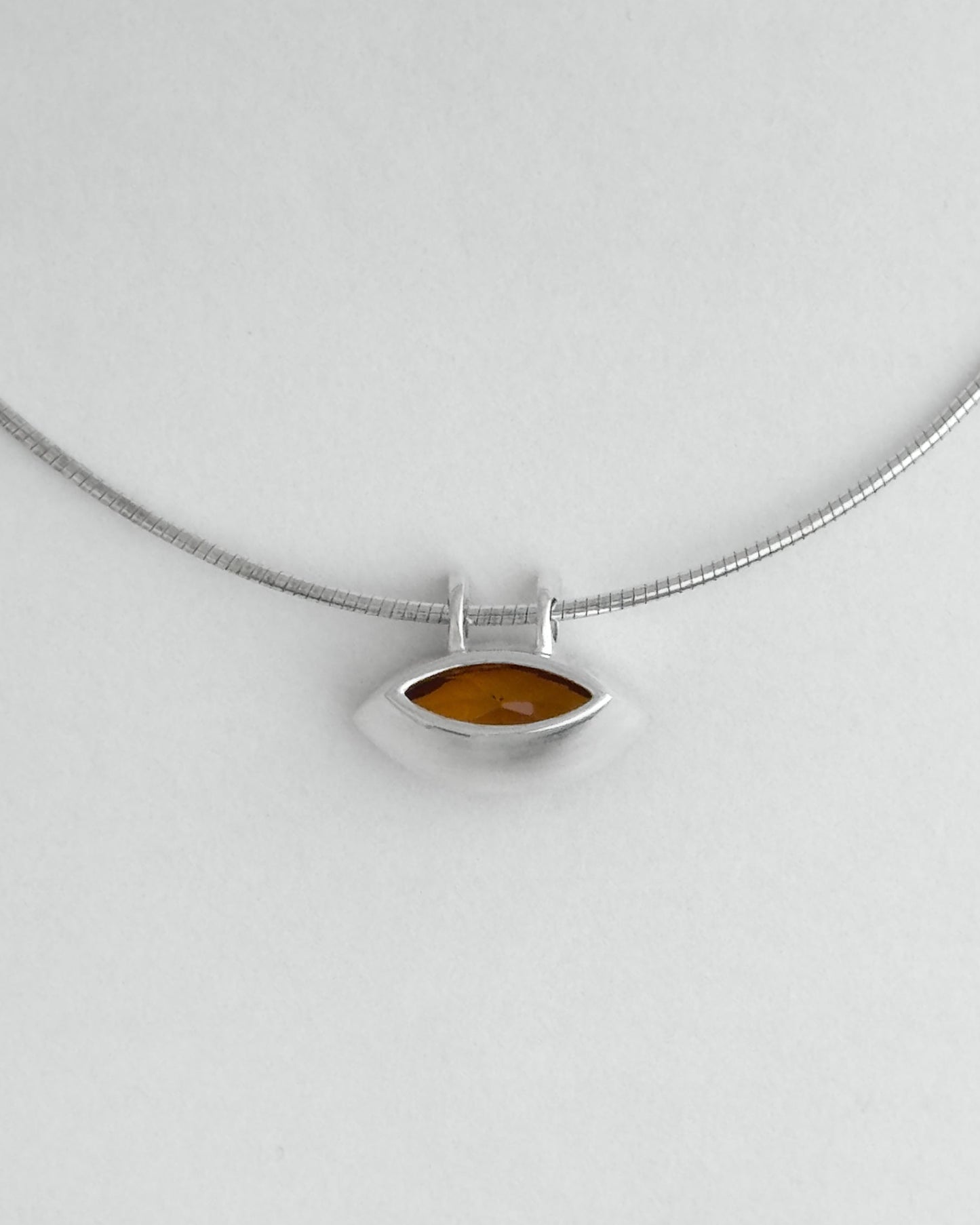 Silver necklace with a citrine pendant on a light gray background