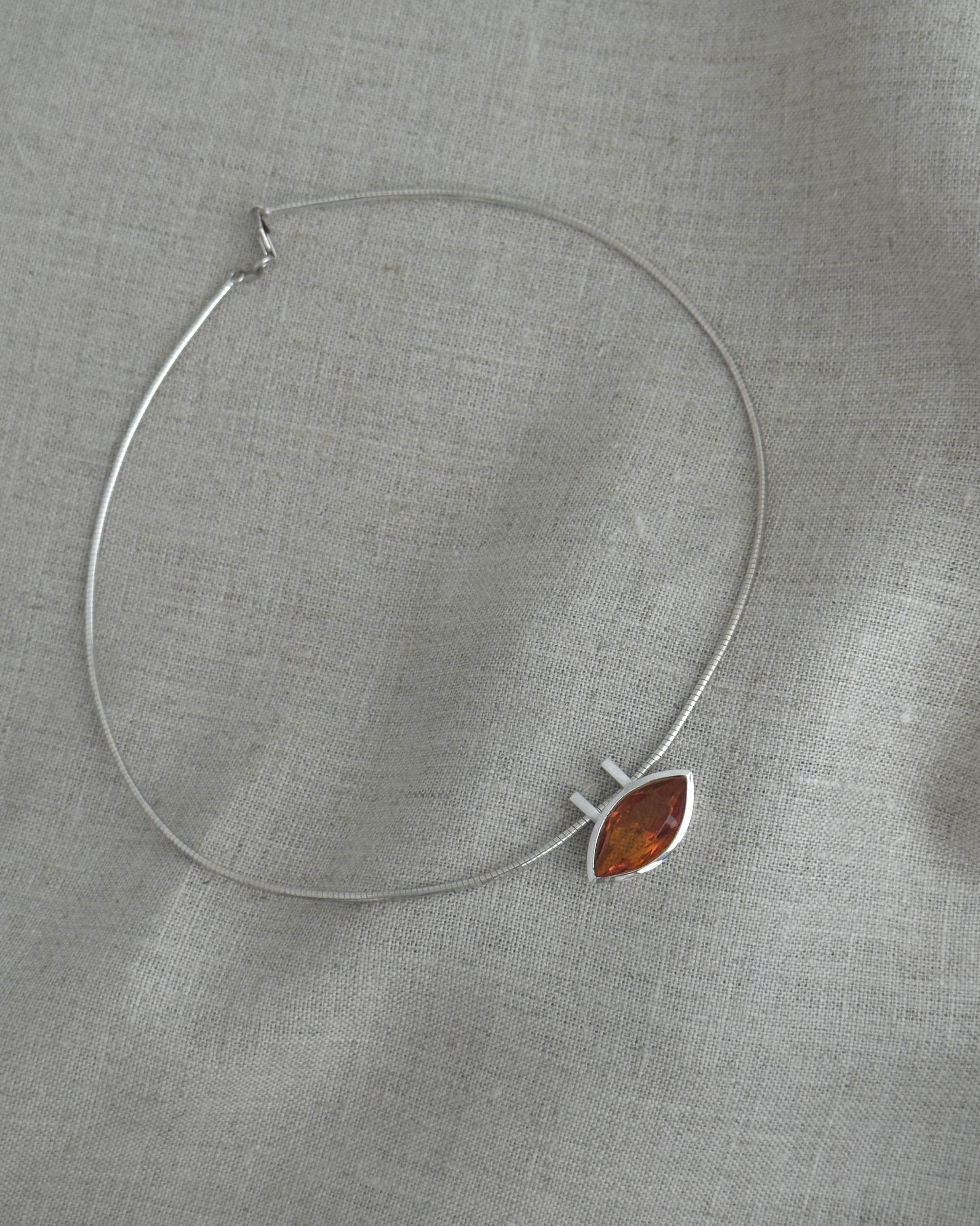 Silver necklace with a citrin pendant on a gray fabric background