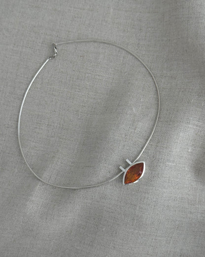 Silver necklace with a citrin pendant on a gray fabric background