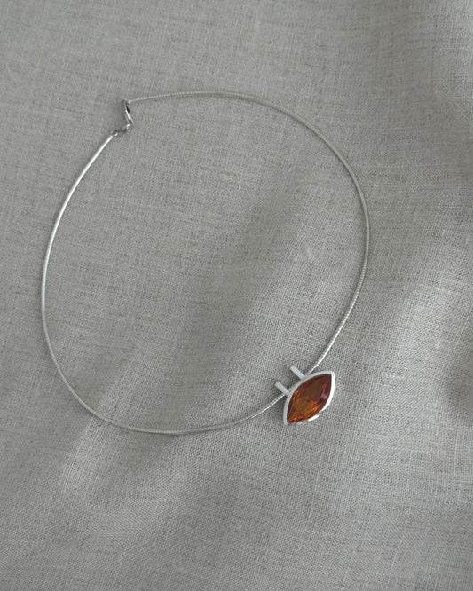 Silver necklace with a citrin pendant on a gray fabric background