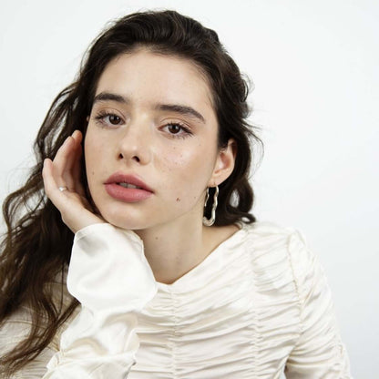 Woman with calm face looking in the camera, leaning her face on her hand