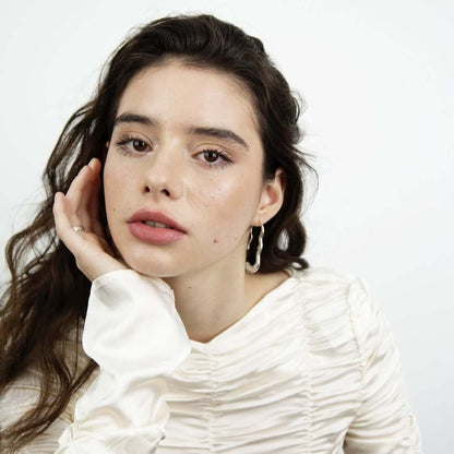 Woman with calm face looking in the camera, leaning her face on her hand