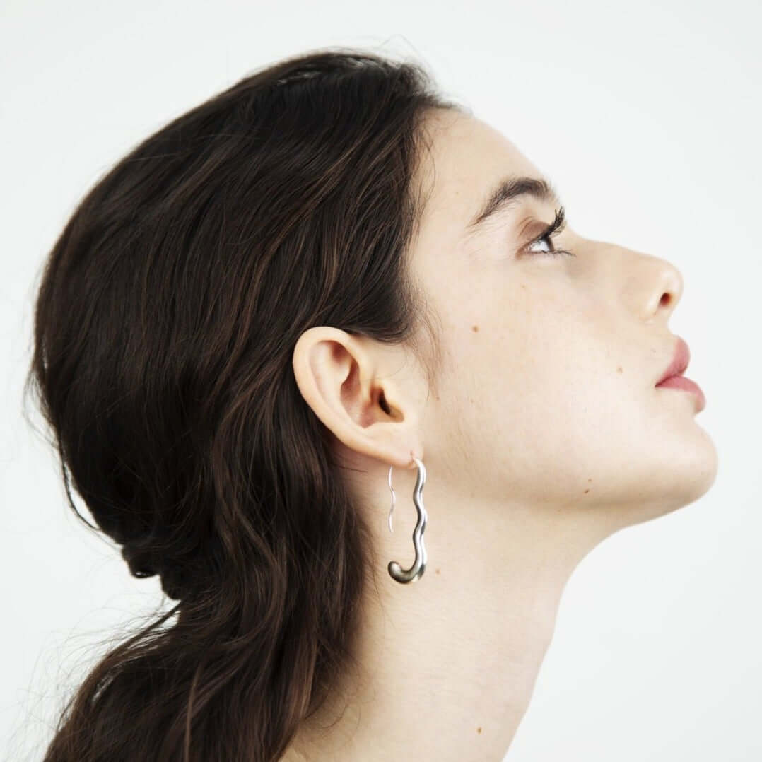 Woman looking up, photo taken of her profile. Wearing silver earrings