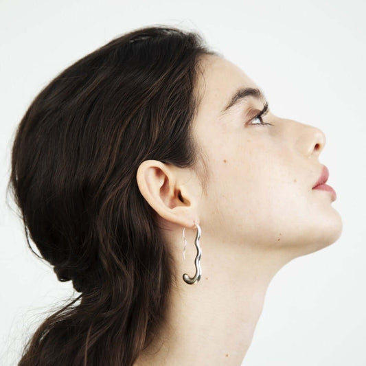 Woman looking up, photo taken of her profile. Wearing silver earrings