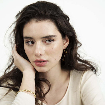 Woman with calm face, leaning on her hand. Wearing jewelry
