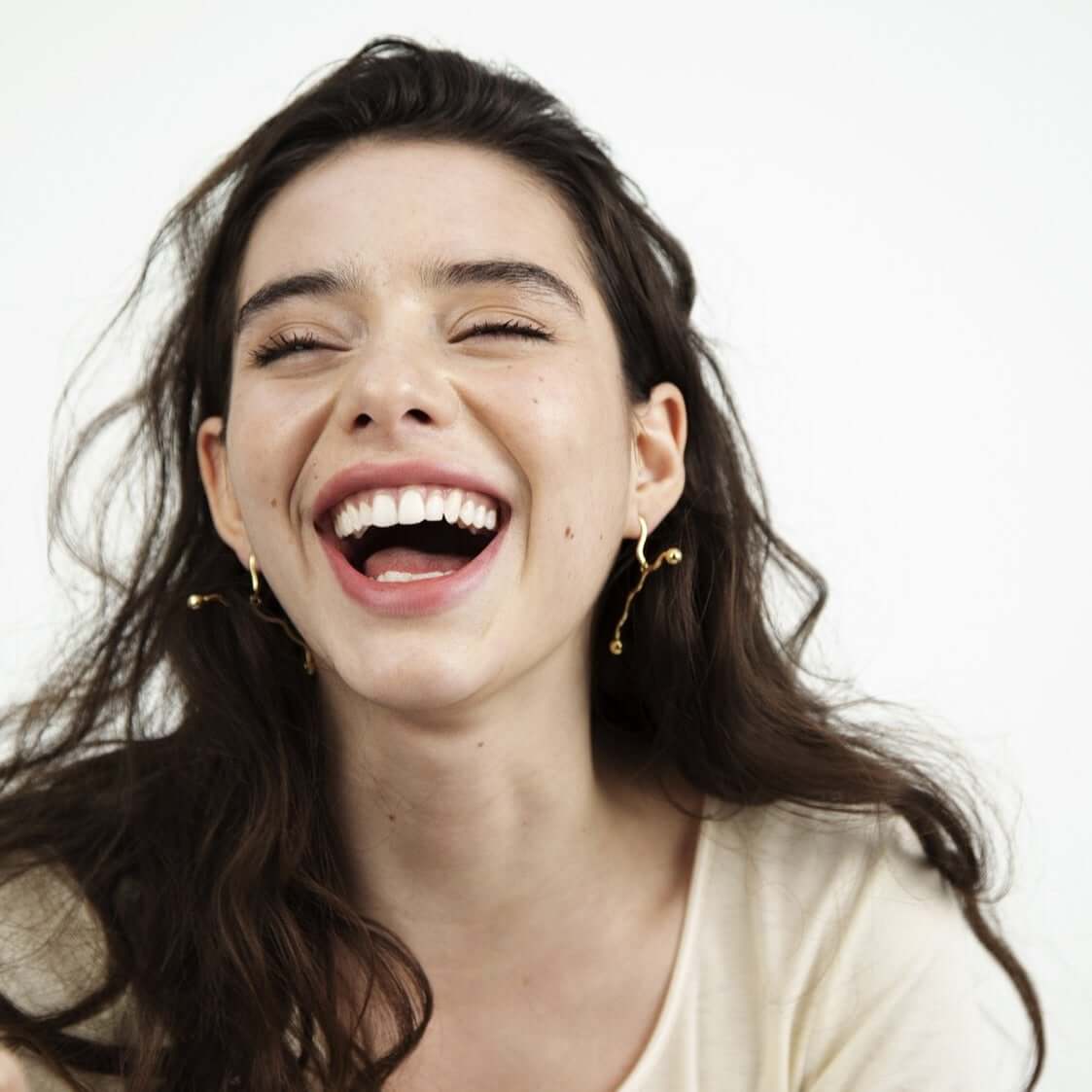 Laughing woman with dark hair and earrings