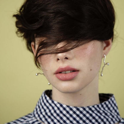 Woman with earrings and lipstick, green background