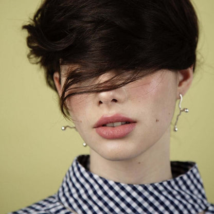 Woman with earrings and lipstick, green background