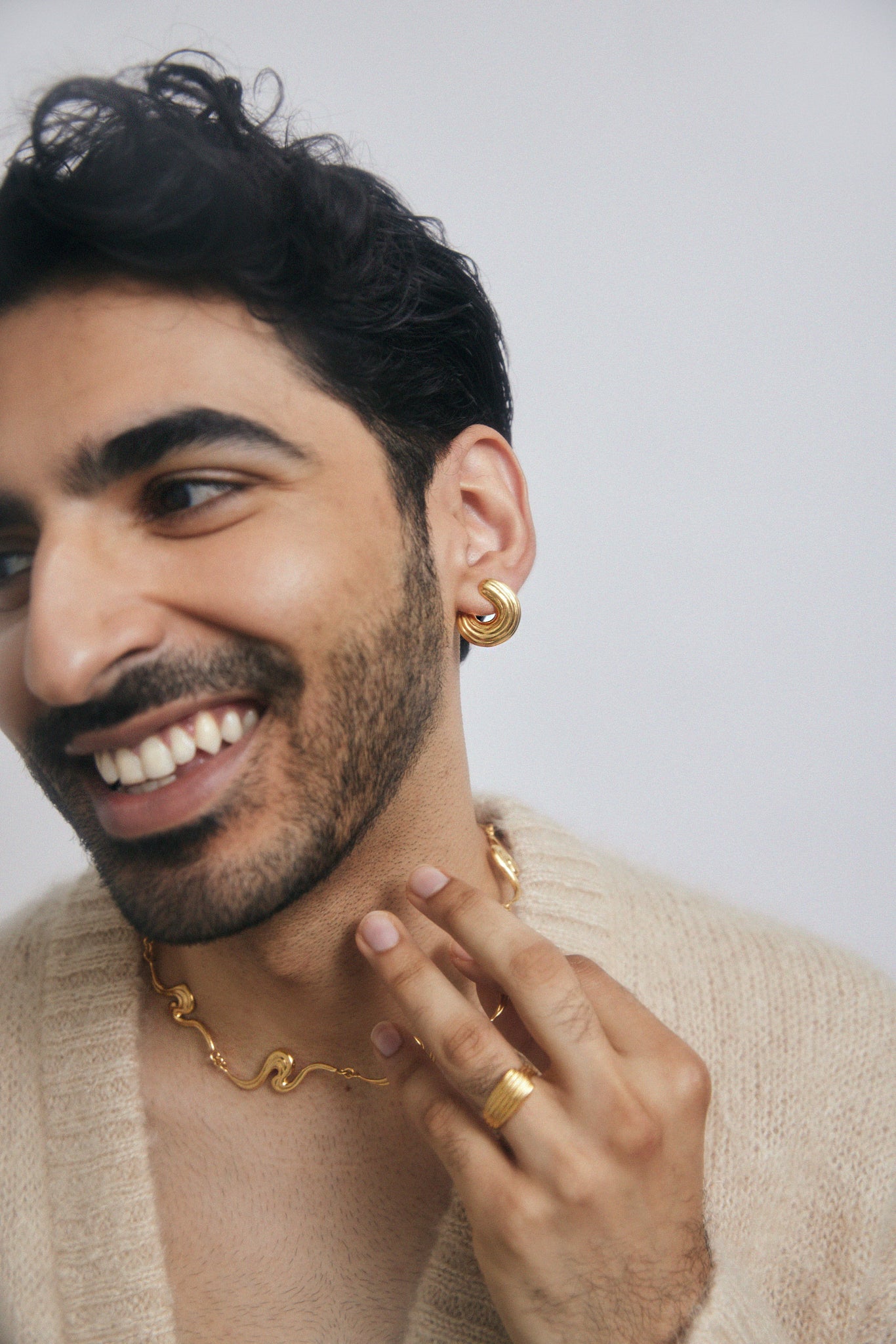 Male model wearing gold jewelry, smiling