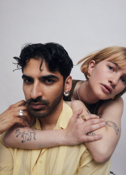 Two models with jewelry and tattoos, wearing yellow shirt