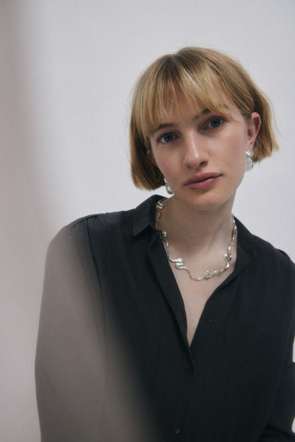 Woman in dark shirt, wearing jewelry