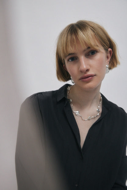 Woman in dark shirt wearing jewelry