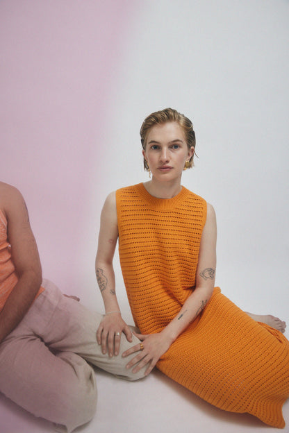 Woman in orange dress, wearing gold earrings