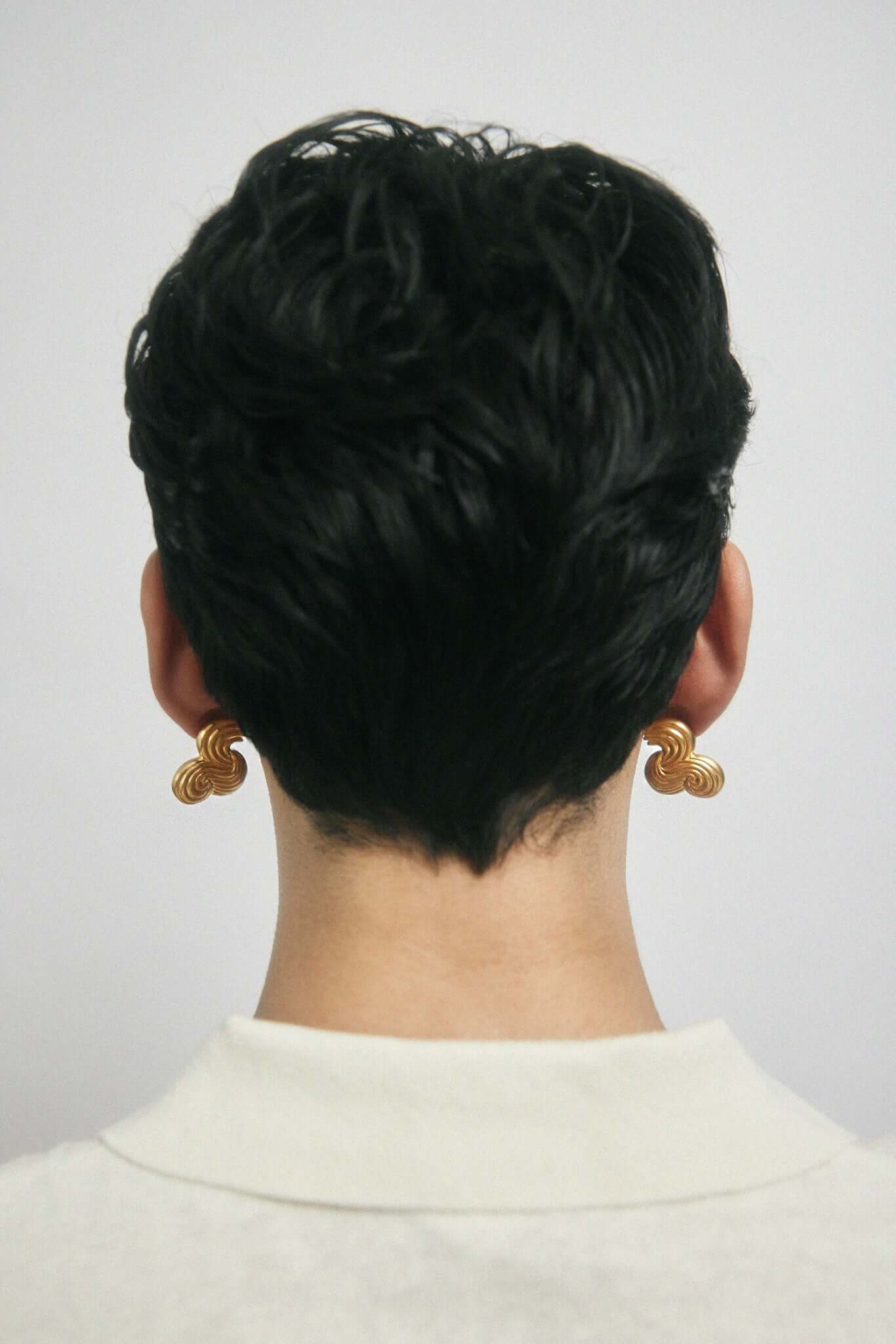 Backside of a mans head, wearing large gold earrings