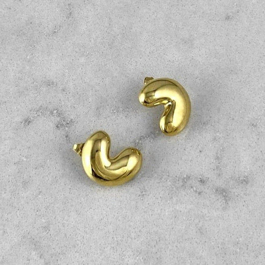 A pair of gold earrings laying on a marble plate
