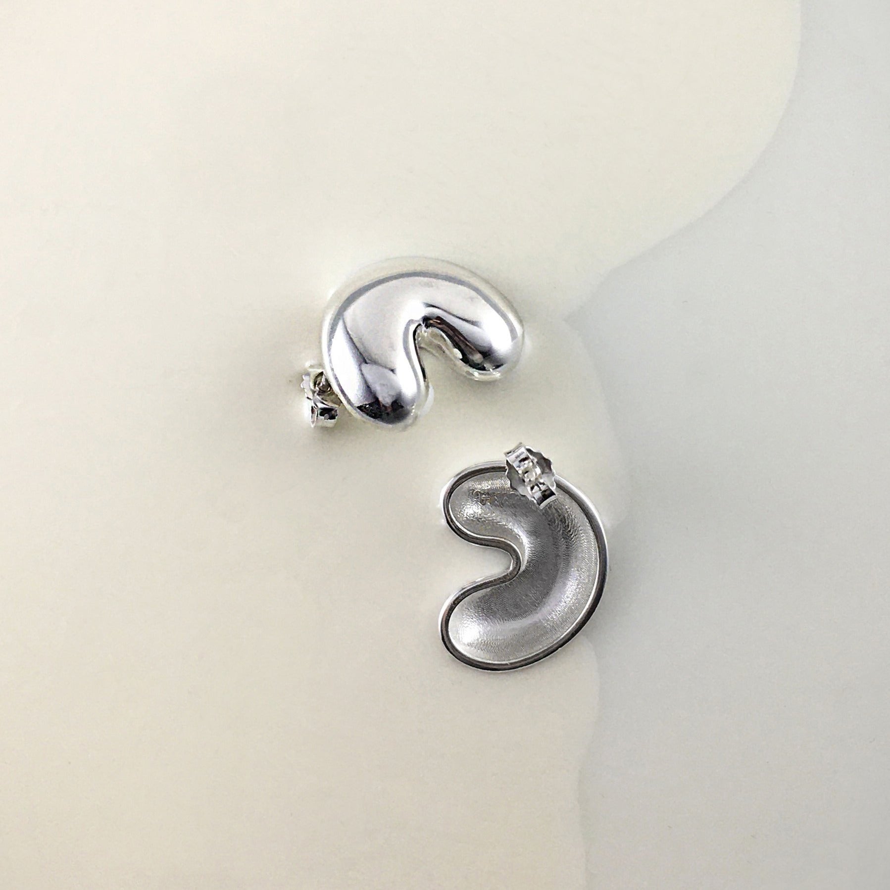 A pair of silver earrings, laying in milk
