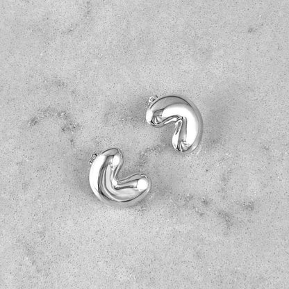 A pair of gold earrings laying on a marble plate