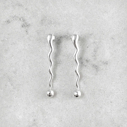 Product photo of a pair of silver earrings on a marble plate