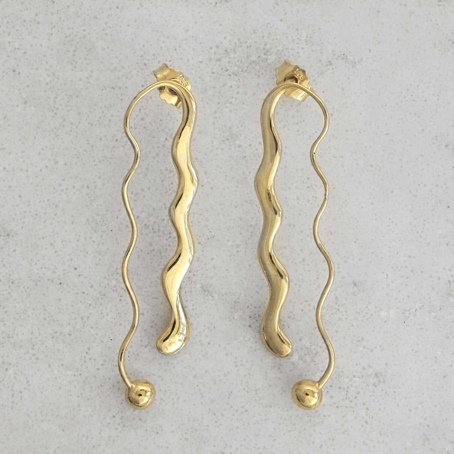 Product photo of a pair of gold earrings on a marble plate