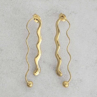 Product photo of a pair of gold earrings on a marble plate