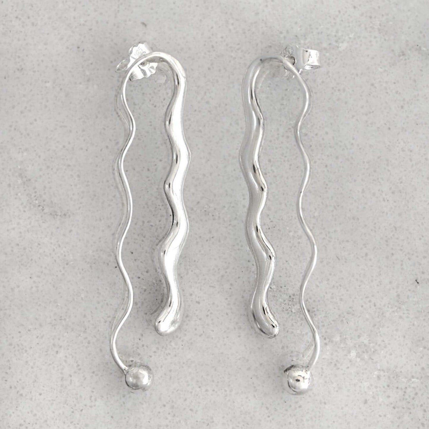 Product photo of a pair of silver earrings on a marble plate