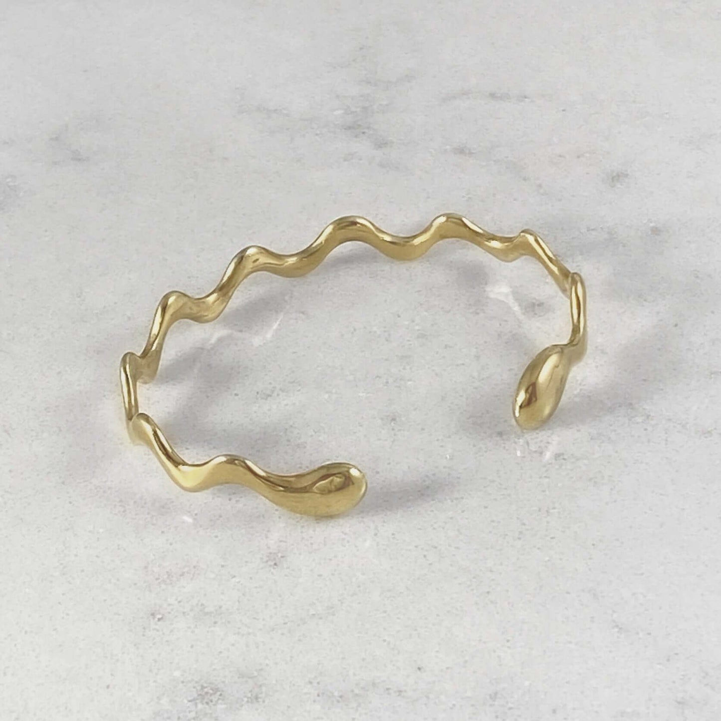 Product photo of a gold bracelet on a marble plate