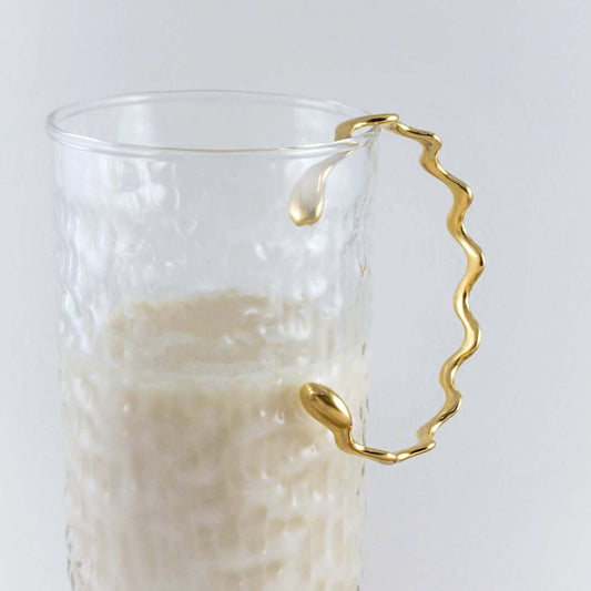 Gold bracelet hanging on a glass of soy milk
