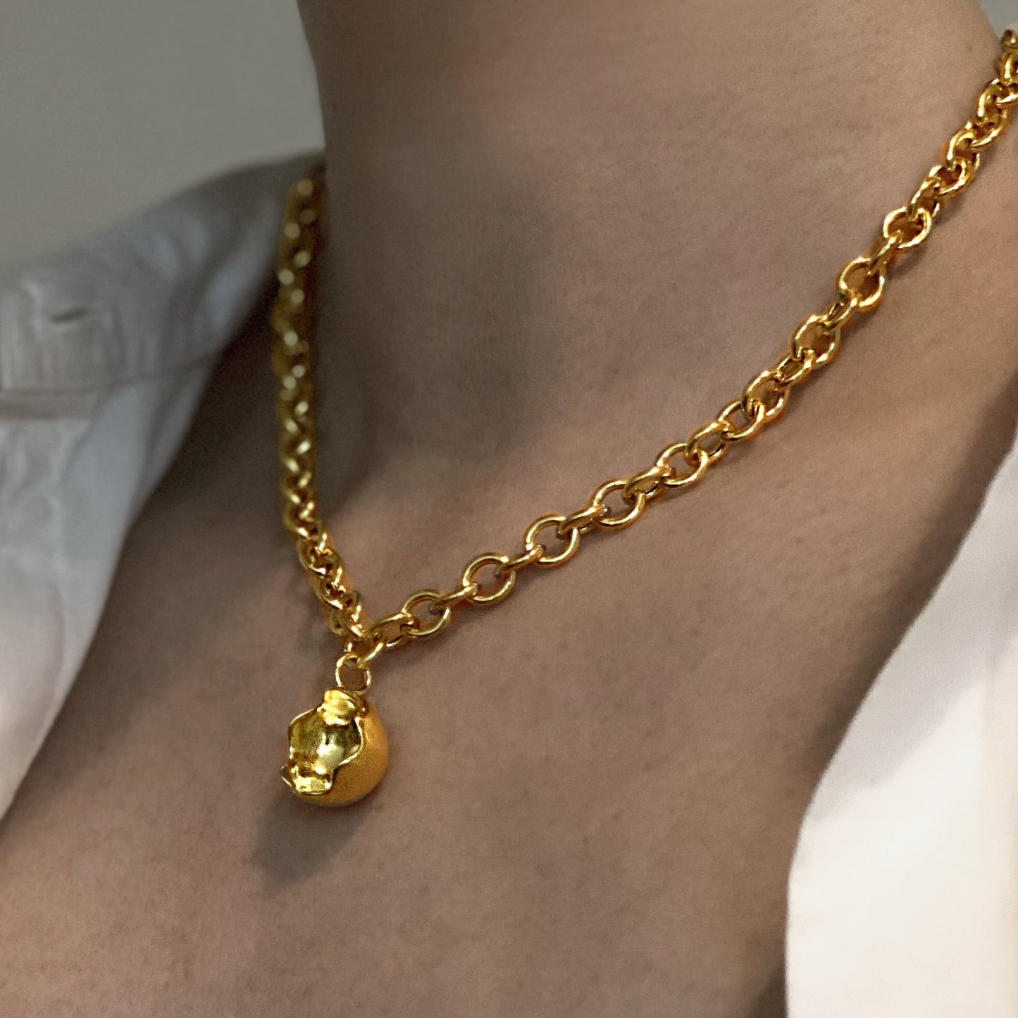 Close up of female neck and chest wearing a chunky chain necklace in gold