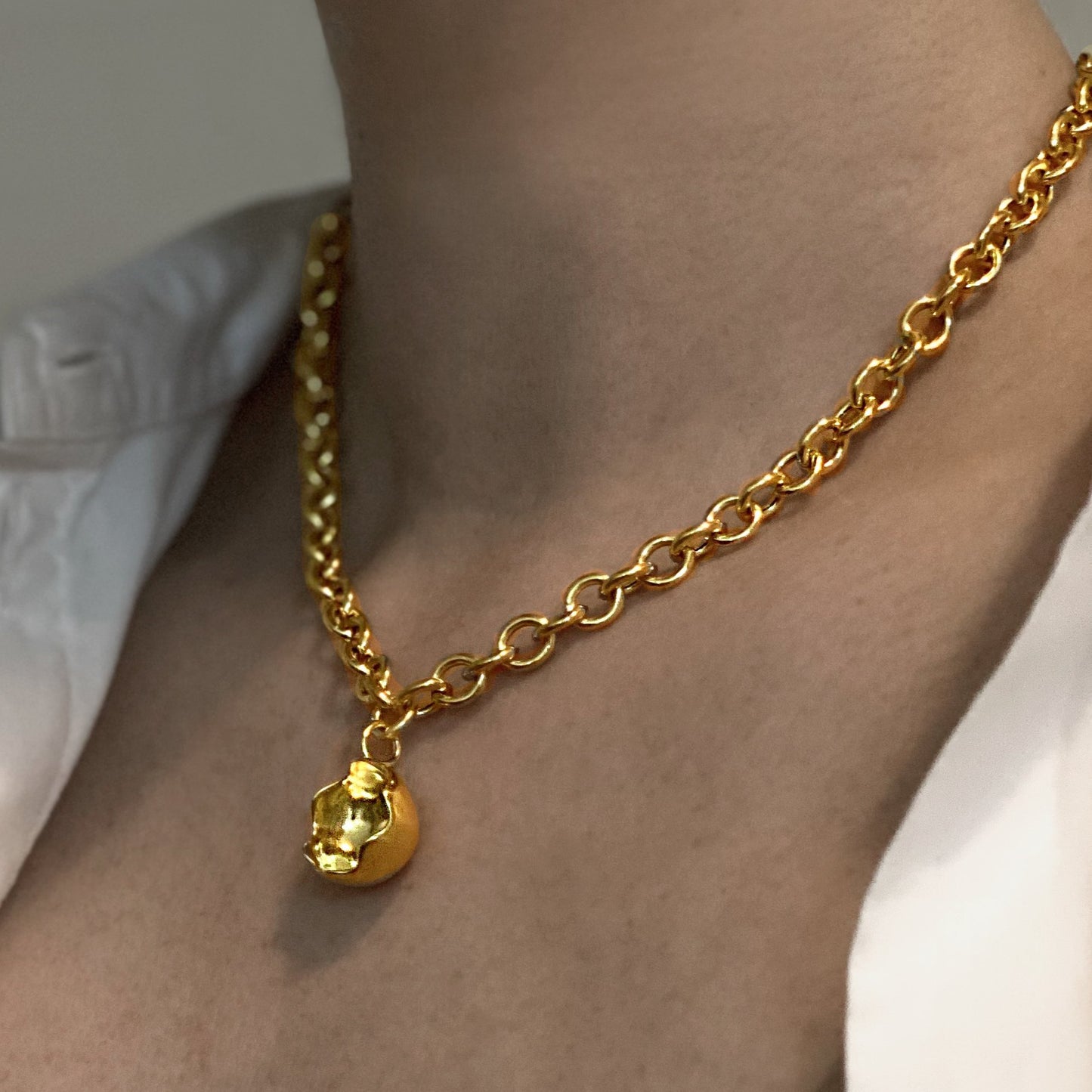 Close up of female neck and chest wearing a chunky chain necklace in gold